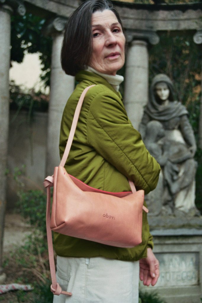 Woman in green jacket carying pink leather bag