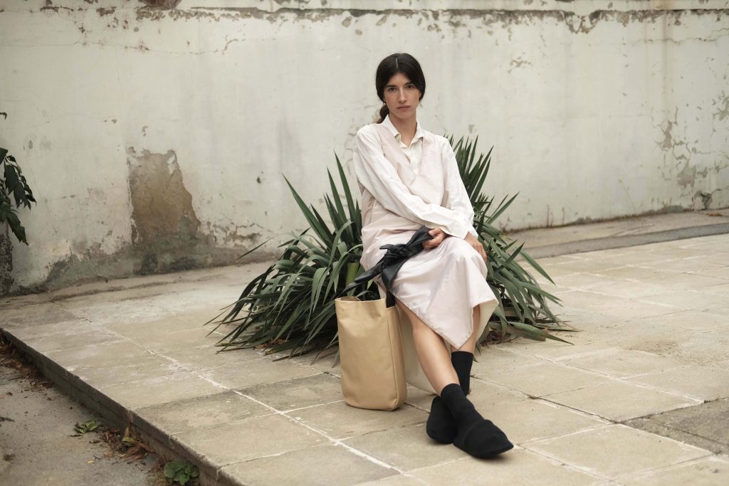 Woman in a silk long reversible dress with a beige lightweight leather shopper