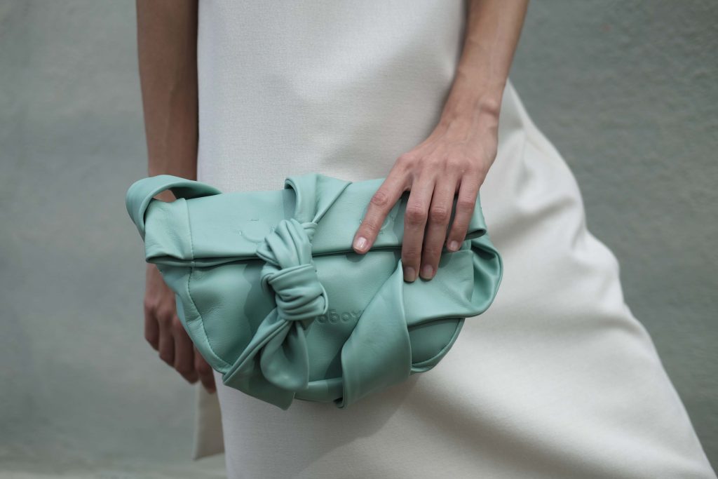 Woman in white holding mint small leather bag